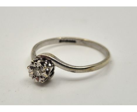 A 9ct. white gold single stone diamond cross-over style ring,&nbsp;illusion set single round cut diamond, size UK O. (gross w