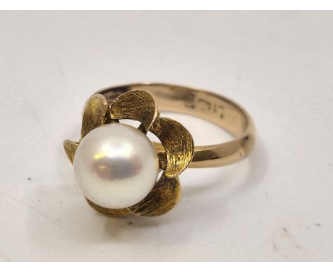 A yellow metal and cultured pearl ring, of flower form, set single cultured pearl above six scalloped and textured petals (ye