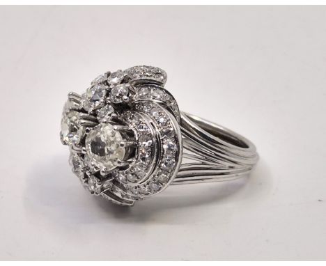 An Art Deco style platinum diamond cluster ring, the raised and stepped mount old cut diamonds across centre with an estimate