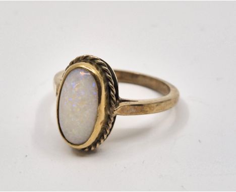 A 9ct. gold and opal ring, with oval cabochon opal in rub-over setting to centre, size UK Q. (gross weight 4.5g)