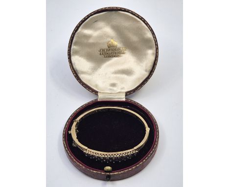 A 9ct. gold, diamond and ruby hinged bangle, the front pave set three rows of alternating round brilliant cut diamonds with a