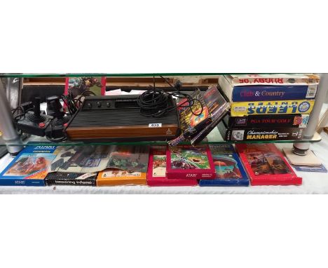 A vintage Atari wood grain games console and selection of games and controls