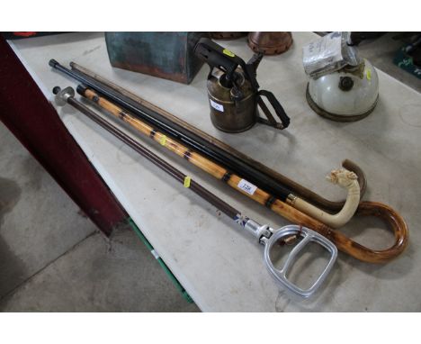 A shooting stick and three various walking sticks