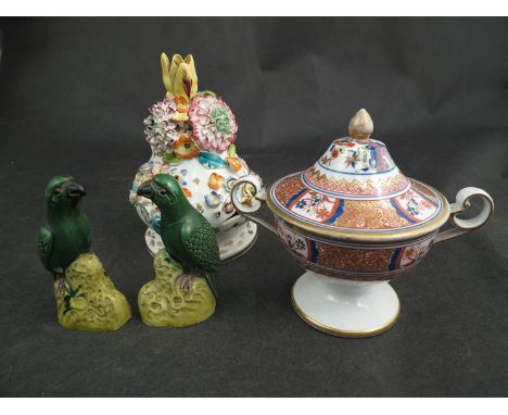 A pair of ornamental green ground porcelain parrots, a lidded Imari pattern pot and an applied floral design finial 