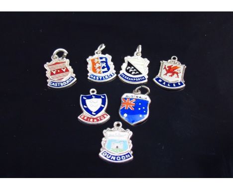 Seven miniature enamel shields depicting various countries including Australia, Wales, England 