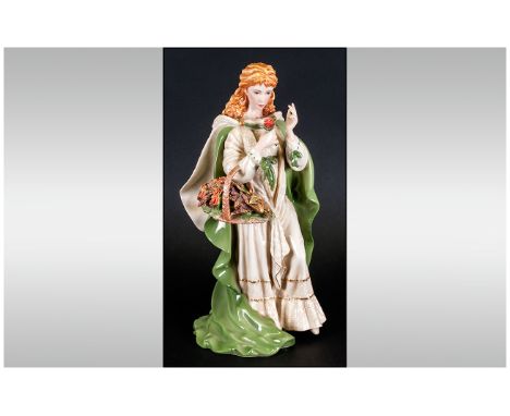 A Fine Hand Painted Ceramic Figure of a Young Woman In Flowing Robes, Holding a Basket of Roses. Stands 11.5 Inches High. 