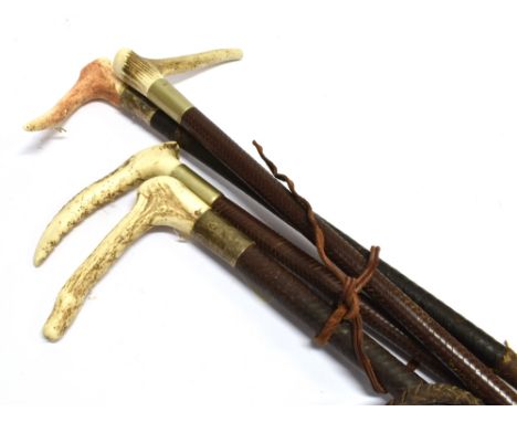 FOUR ASSORTED HUNTING CROPS (three by Swaine), with antler grips and plaited leather shafts and three with plaited leashes 