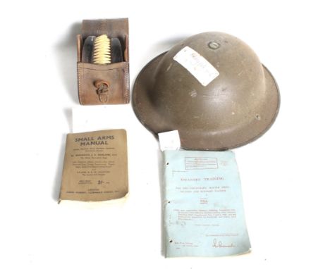 A WWII helmet, brushes and box belonging to the Cox family. The helmet and a 1944 'Infantry Training' book both with label ma