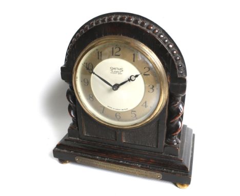 A Smith's carved wood cased mantel clock. Eight day, four jewel mechanical movement, in an arch top oak case with twist colum