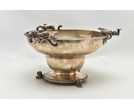 A GEORGE V SILVER PEDESTAL BOWL, with three cast handles, each formed of two serpents and two lion dormant with the tails wra