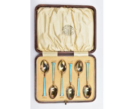 A CASED SET OF SIX GEORGE V SILVER GILT AND ENAMEL COFFEE SPOONS, the handles engine turned and enamelled in a peacock blue, 