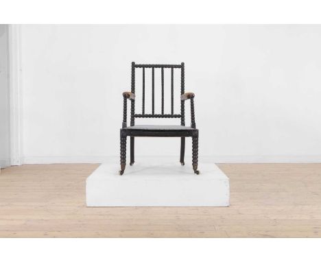 An ebonised bobbin-framed nursing chair, 19th century, with padded leather arms and an upholstered seat, raised on bobbin-tur