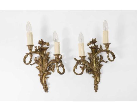 A pair of Louis XV-style gilt-brass wall lights, late 19th/early 20th century, French, each of scrolling foliate form, issuin