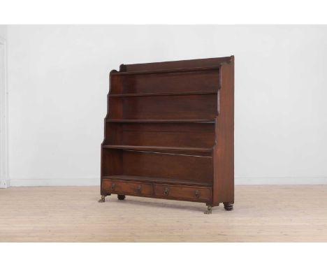 A large Regency mahogany waterfall bookcase, c.1820, the reeded frame with five shelves over two drawers and raised on brass 