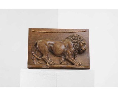 A carved wood panel of the Barberini Lion, 20th century, depicted in high relief, in profile with tail wrapped around its bac