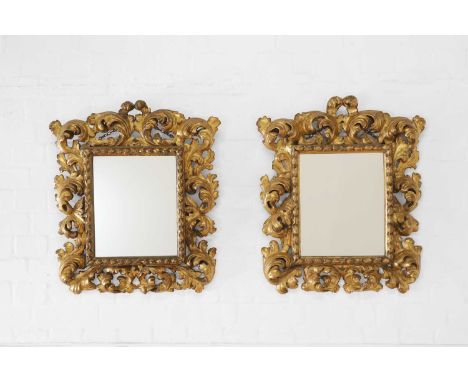 A pair of carved giltwood mirrors, 19th century, Italian, Florence, each with a bold foliate frame, enclosing a later glass p