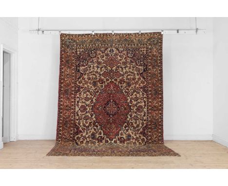 A Persian wool carpet, early 20th century, Isfahan, woven with scrolling Shah Abbasi motifs to a cream and red ground, 340 x 