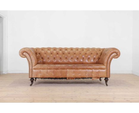 A tan leather chesterfield sofa, 20th century, with studded and buttoned decoration, raised on brass cap castors,220cm wide10