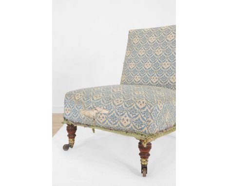 A late Victorian nursing chair by Howard & Sons, c.1890, covered in blue and white ticking, and raised on ring-turned front s