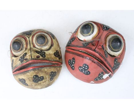 Two mid 20th century folk art tribal wooden hand painted frog masks with articulated jaws, H 17cm