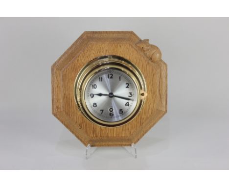 A Robert Mouseman Thompson wall clock bulkhesd style windup clock with silvered dial, on carved octagonal oak mount with sign