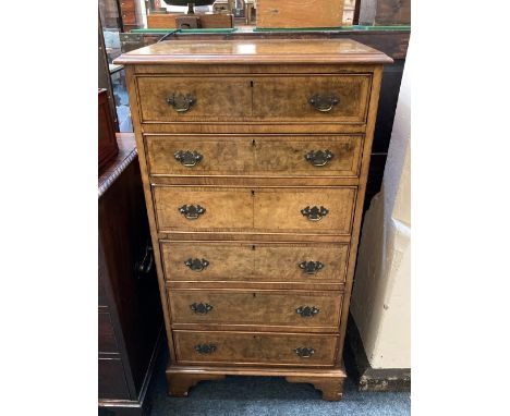 A reproduction walnut narrow chest of six graduated drawers with crossbanded top and drawers, drop handles on bracket feet, 5