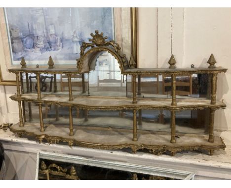 A 19th century continental two-tier wall shelf possibly Italian, with arched cornice, turned supports, carved gesso decoratio
