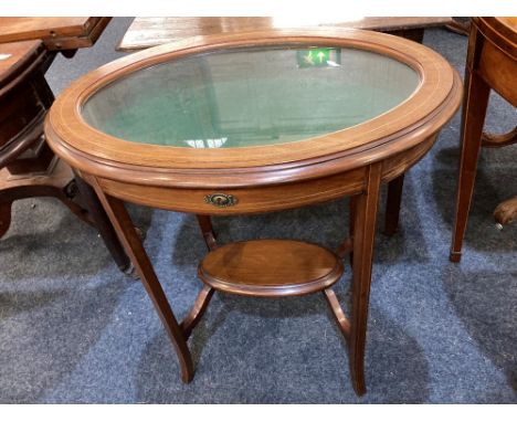 A mahogany vitrine of oval form, with line inlaid detail, on slender curved legs united by an oval stretcher shelf, 66cm