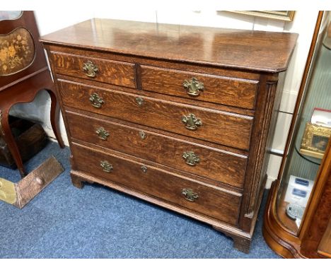 A George III oak chest of two short over three long drawers with fluted corners, brass drop handles on bracket feet, 110cm