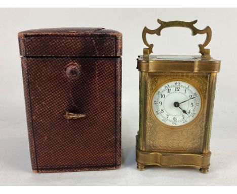 A brass carriage clock with white circular enamel dial and arabic numerals within gilt scroll face, with case, 15cm high