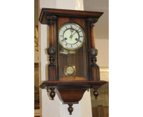 A mahogany Vienna style wall clock with circular 14cm white enamel dial, in glazed rectangular case with carved column uprigh