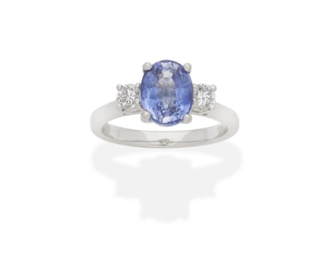 SAPPHIRE AND DIAMOND THREE-STONE RINGOval-cut sapphire and brilliant-cut diamonds, mounted in platinum, UK hallmark, ring siz