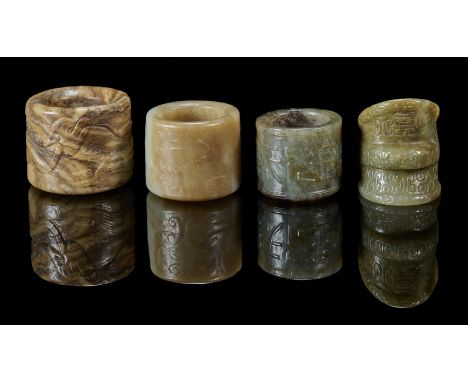 comprising: a celadon and brown jade ring carved with C-scrolls, 2.7cm high; a green jade ring carved with archaistic scrolls