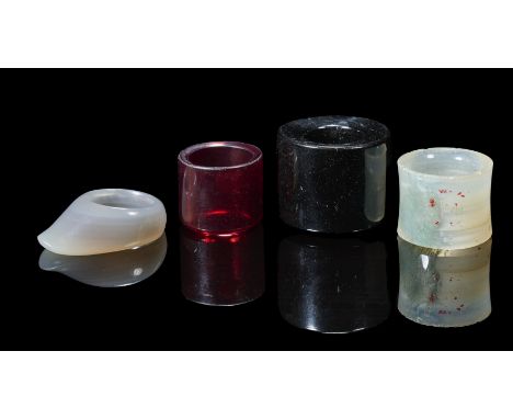 comprising: a large ink-amber ring, 3cm high; a moss agate ring, 2.2cm high; an agate ring, 4.3cm long; and a ruby glass ring