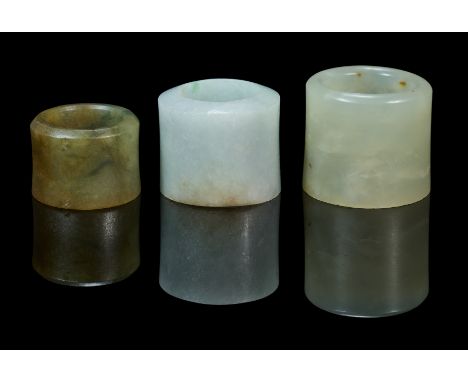 comprising: a pale celadon jade ring with tiny russet inclusions, 2.7cm high; a celadon jade ring, 2.7cm high; a small greyis