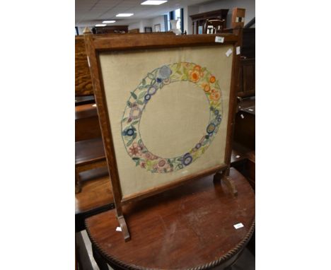 A vintage oak framed fire screen having embroidered panel