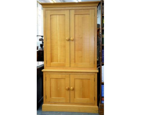 A MODERN LIGHT WAXED OAK CUPBOARD ENCLOSED BY TWO PAIRS OF PANELLED DOORS, 104CM W 