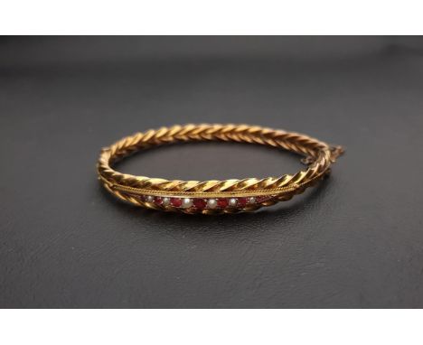 RED GEM AND SEED PEARL NINE CARAT GOLD BANGLEthe hinged bangle with rope twist detail, approximately 10.3 grams 