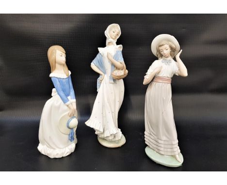 THREE NAO FIGURINEScomprising a girl holding her hat, 28cm high, a girl holding a basket of flowers, 33cm high, and a girl we