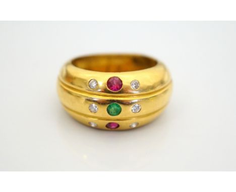 DIAMOND, RUBY AND EMERALD DRESS RINGin eighteen carat gold, ring size L and approximately 6.1 grams