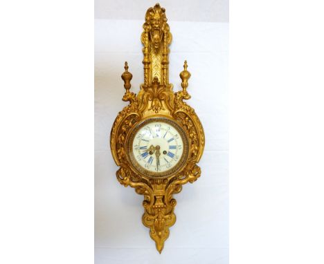ORMOLU CARTEL CLOCKsurmounted with a mask above twin turned columns with urns above a pair of lion heads and garlands, the ci