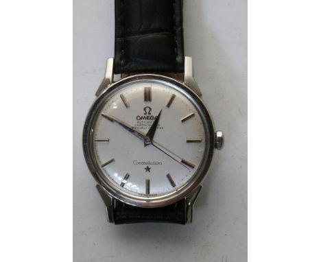 A gents automatic Omega Constellation chronometer wristwatch in a wood box with batons to the off-white dial, set on a black 