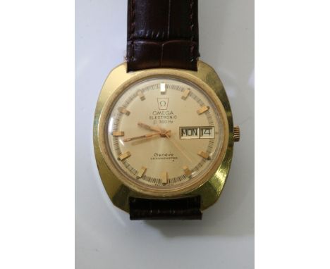 A gents Omega F300 day-date chronometer watch of brass colour mounted on a brown leather strap