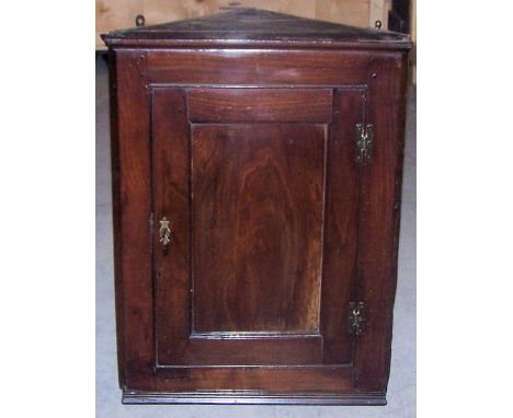 An early 19th century oak Corner Wall Cupboard, the interior with a serpentine fronted shelf and enclosed by a single panelle