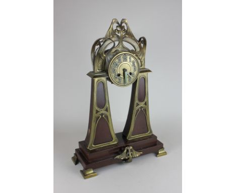 An Art Nouveau brass mantle clock, the green painted Arabic numerals on circular brass face with stylised leaf surround on pa