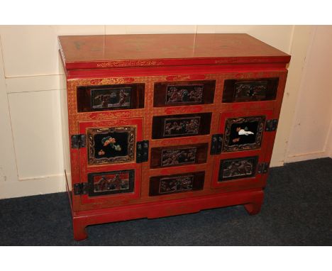 A Chinese red lacquer chest of three short drawers over two cupboards and three drawers, the drawers with carved wood detail,