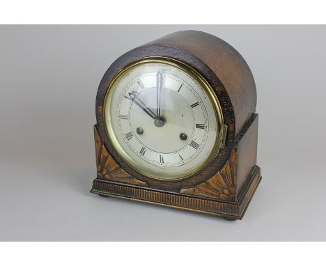 An oak cased mantle clock with raised carved floral detail, the silverised case with Roman numerals, the movement marked Brit