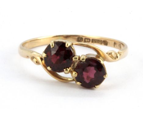 A 9ct yellow gold garnet set crossover ring, (O).