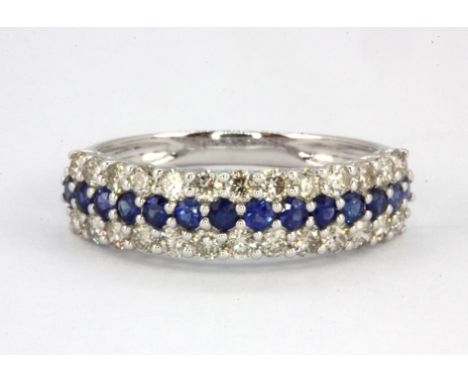 An 18ct white gold (stamped 750) half eternity ring set with a row of round cut sapphires flanked by two rows of brilliant cu