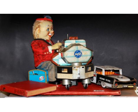 A tin police car toy and two other vintage tin toys.